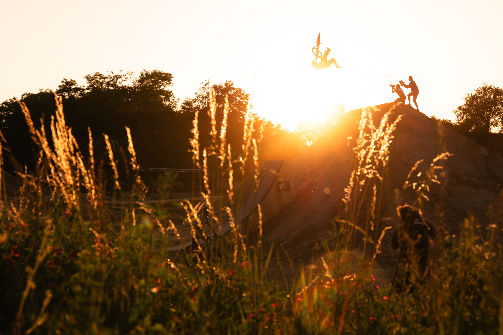 Daniel Ruso mid-flip silhouetted against a golden sunset on the dirt jumps